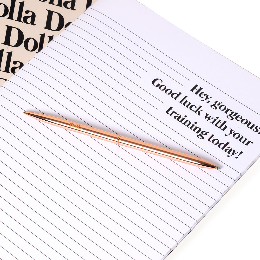 rose gold think pen laying on the page of an opened notebook