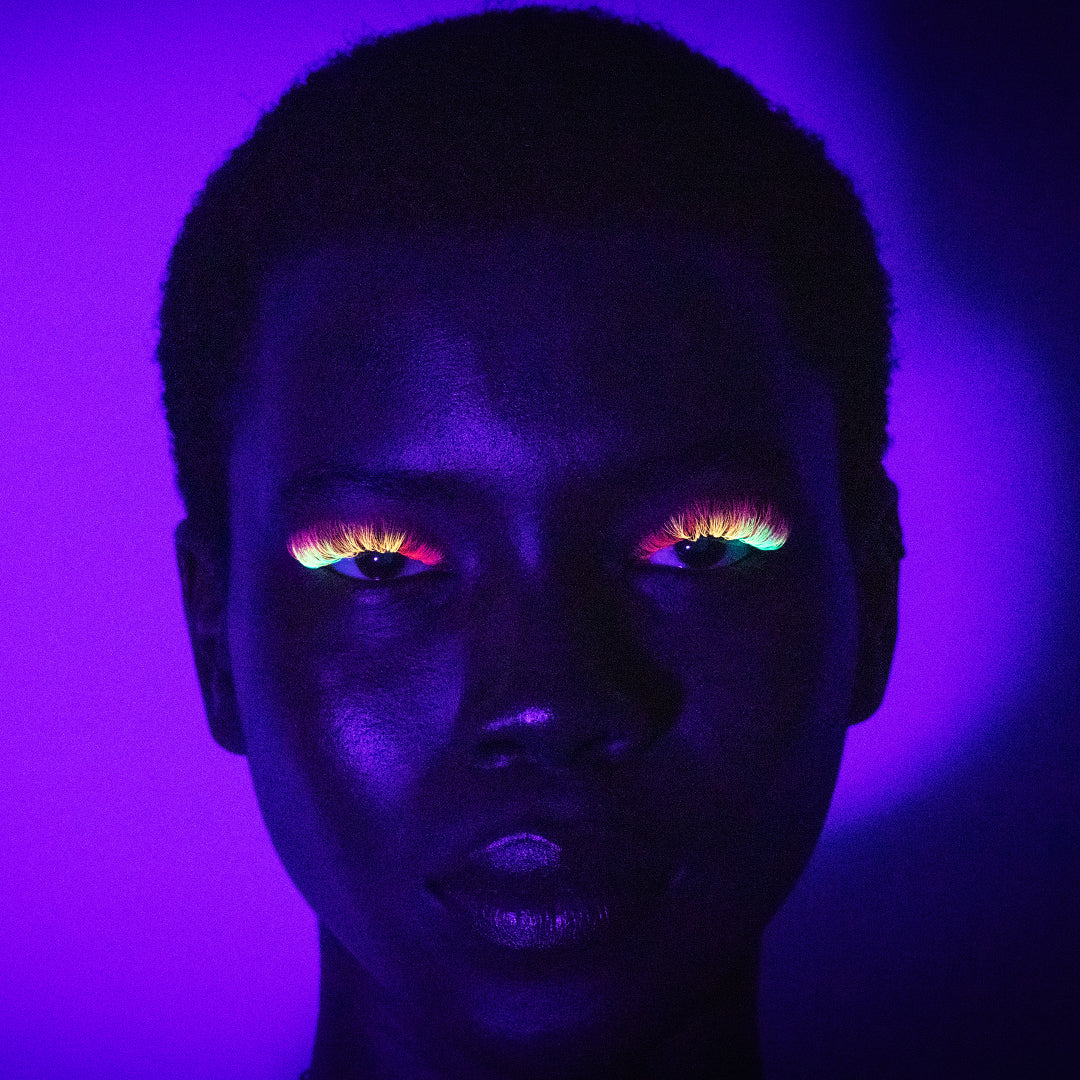 Face of model wearing london lash neon lashes in a dark background to showcase the bright colours