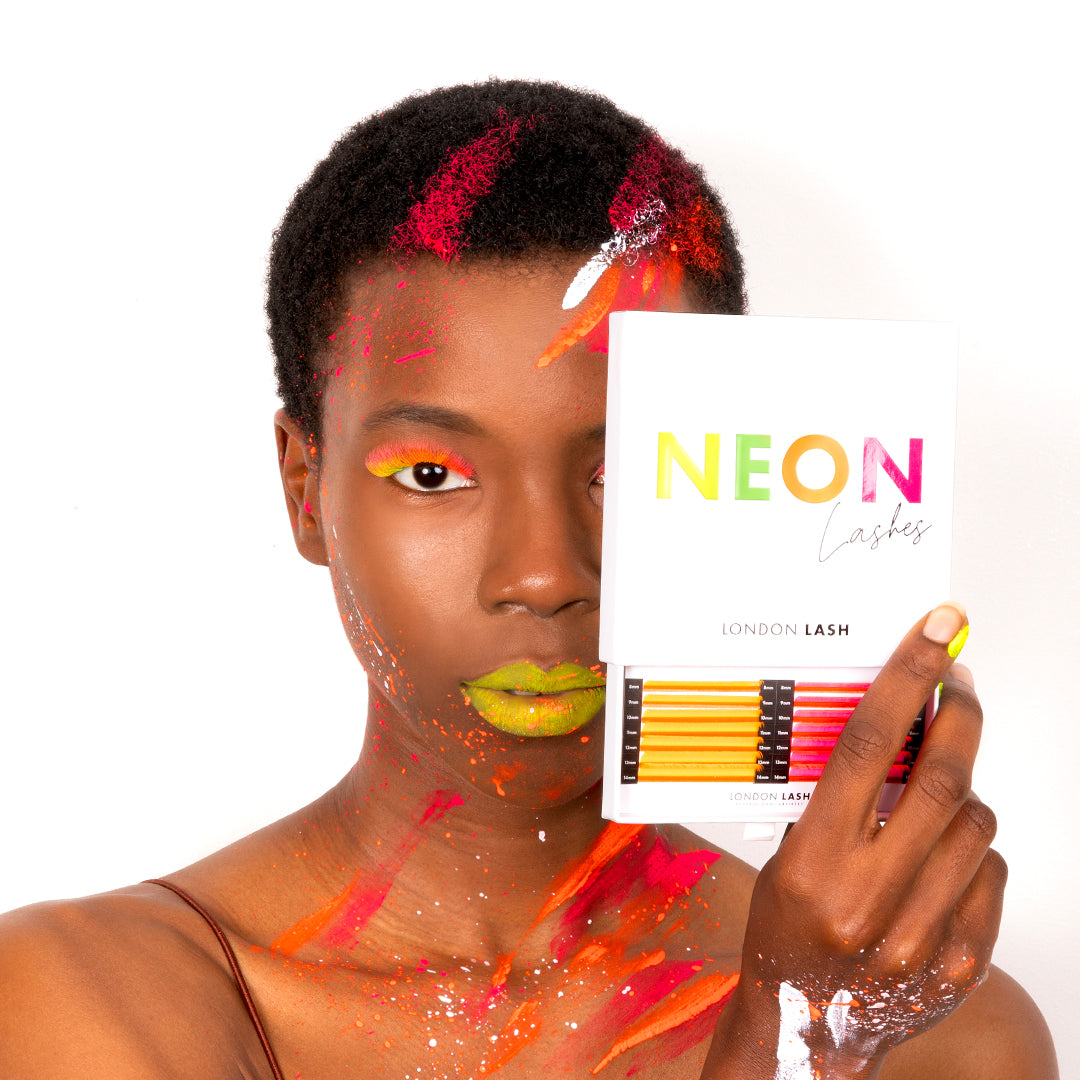 Close up of model wearing  London lash neon coloured eyelash extensions and holding the Neon lash tray showcasing the  yellow and pink colours
