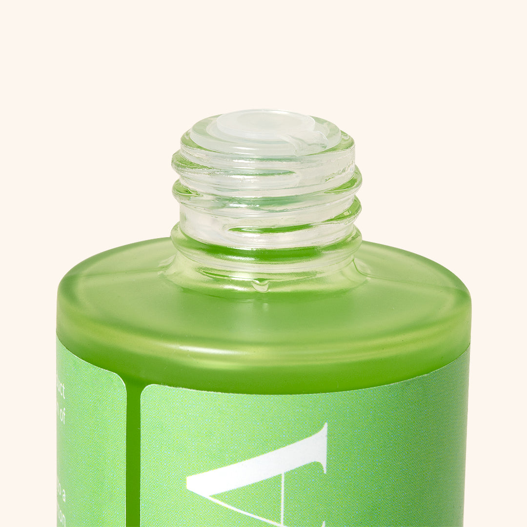 the top of the transparent bottle with green henna stain remover liquid inside